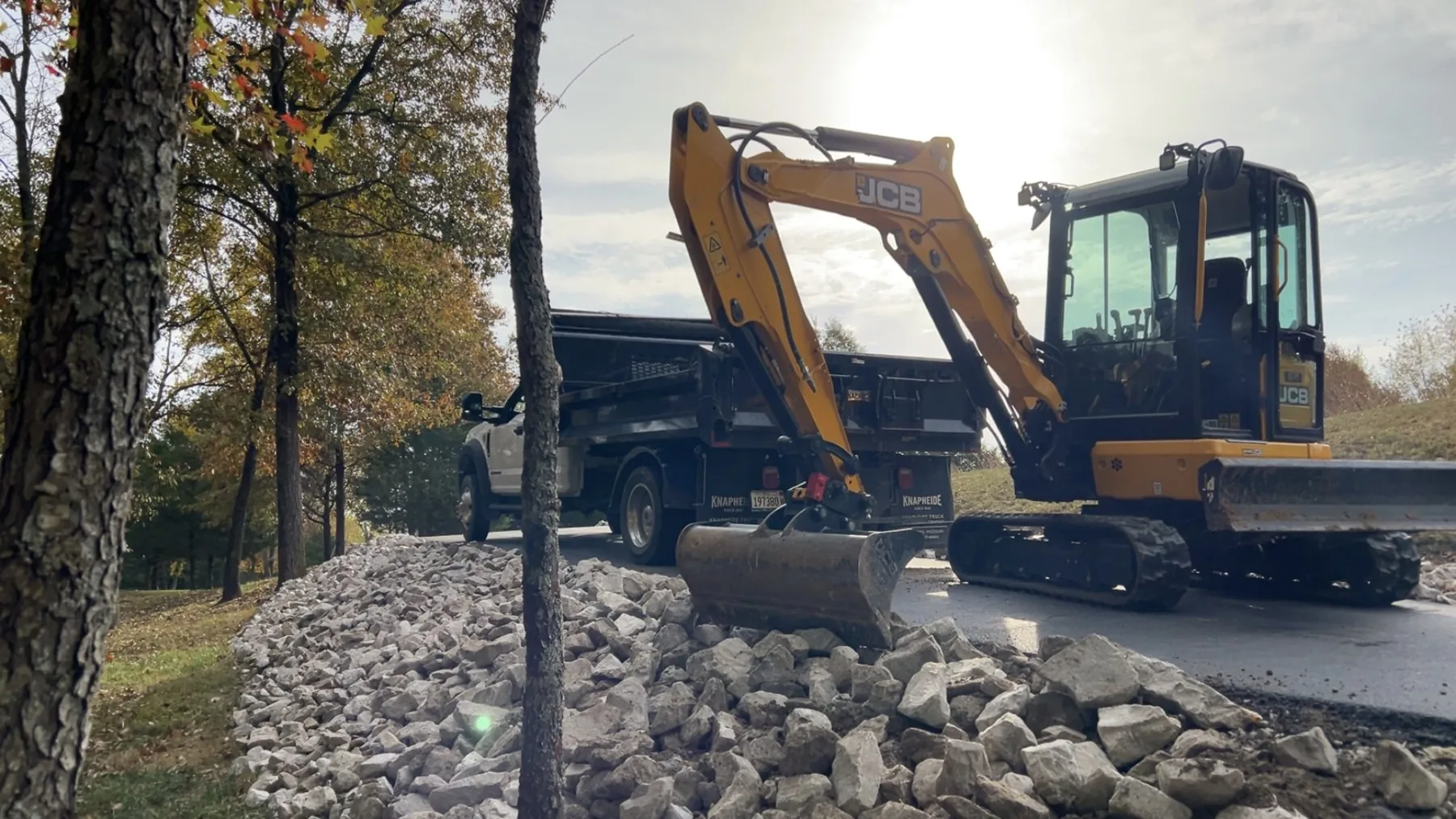 Excavator placing stone for grading and erosion control near water